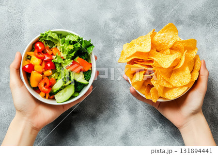 Unhealthy vs healthy food. vegetable salad and potato in different hands on green background . Choice between fast foods and vegetables, fruit. Unhealthy vs healthy food. vegetable salad and potato in different hands on green background . Choice between fast foods and vegetables, fruit. 131894441