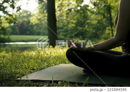 a woman practicing yoga on a mat in a tranquil park at dawn. promoting a healthy and balanced lifestyle. a woman practicing yoga on a mat in a tranquil park at dawn. promoting a healthy and balanced lifestyle. 131894595