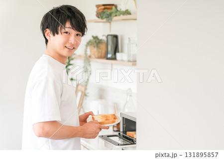 キッチンでトースターでパンを焼く若いアジア人男性 キッチンでトースターでパンを焼く若いアジア人男性 131895857