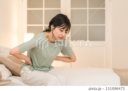夜のベッドルームで腹痛,生理痛に悩む若いアジア人女性 131896473