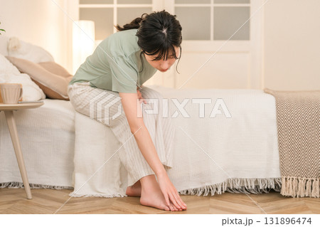 夜のベッドルームでつま先を痛がる若いアジア人女性 131896474