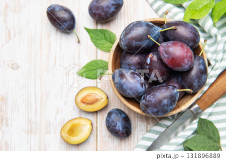 Fresh plums in wooden bowl with knife 131896889