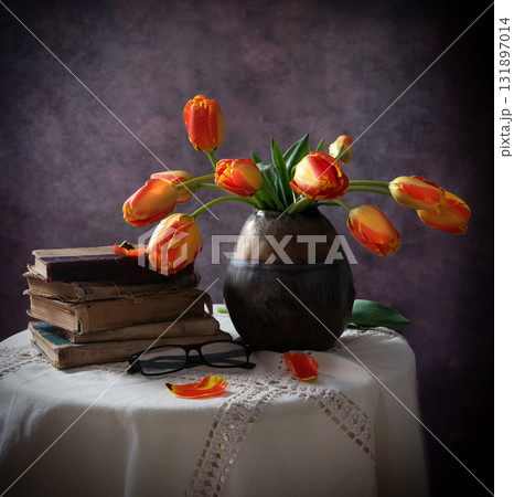 still life with old books and tulips in a dark vase 131897014