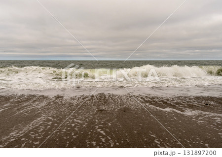 Powerful ocean wave crashing on sandy beach shoreline 131897200