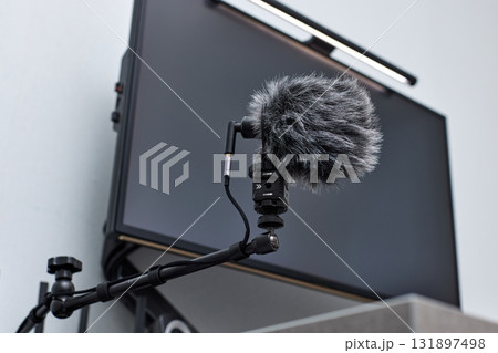 black professional boom microphone stand used for recording voice in online podcast in home studio. fluffy microphone and computer on the table 131897498