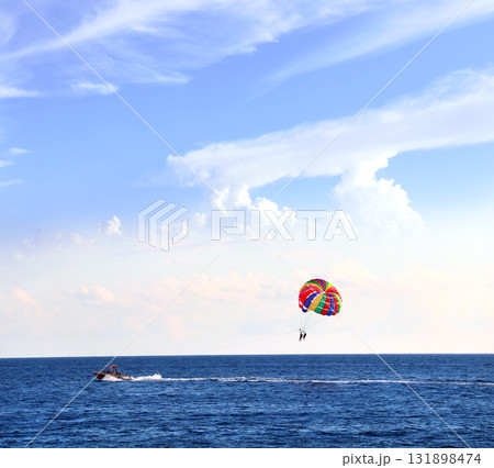 Picturesque view of sea and tourists on a parachute. Topic of summer vacation, travel, leisure and adventure for tourist. Parasailing in the sea. A popular tourist pastime with a parascending Picturesque view of sea and tourists on a parachute. Topic of summer vacation, travel, leisure and adventure for tourist. Parasailing in the sea. A popular tourist pastime with a parascending 131898474