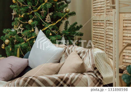 cozy indoors with Christmas tree, blankets, cushions, creating warm atmosphere for holiday. closeup. cozy indoors with Christmas tree, blankets, cushions, creating warm atmosphere for holiday. closeup. 131898598