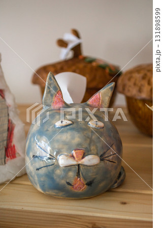 funny handmade ceramic cat sculpture displayed on shelf among other artisan crafts. closeup. 131898599