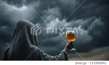 Hooded figure raises a glass of ale against a dramatic, stormy sky, creating a moment of dark celebration. 131898942