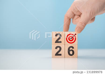 Hand creating 2026 new year business plan with wooden blocks. Man placing dartboard icon to form year number concept Hand creating 2026 new year business plan with wooden blocks. Man placing dartboard icon to form year number concept 131899978