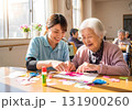 介護士と高齢女性が笑顔で工作を楽しむデイサービスの風景 131900260