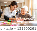 介護士と高齢女性が笑顔で工作を楽しむデイサービスの風景 131900261