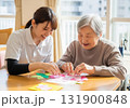 高齢者と介護スタッフが一緒に手作業を楽しむ明るい介護現場 131900848