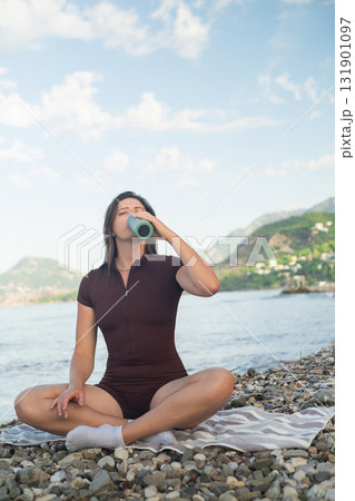 Sporty woman on the seaside enjoying peaceful moment after workout and drinking fresh water. Sporty woman on the seaside enjoying peaceful moment after workout and drinking fresh water. 131901097