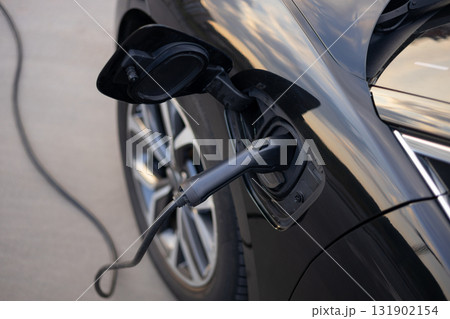 An electric vehicle is charging, with the charging cable plugged into the car's port. 131902154