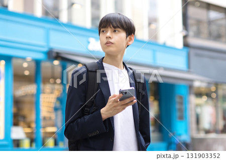 街中でスマホを持って立つ20代男性のビジネスマン 街中でスマホを持って立つ20代男性のビジネスマン 131903352