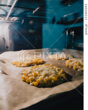Delicious corn fritters baking in hot oven on parchment paper, filling kitchen with mouthwatering aroma while achieving perfectly golden brown texture and irresistible appeal. Golden corn fritters Delicious corn fritters baking in hot oven on parchment paper, filling kitchen with mouthwatering aroma while achieving perfectly golden brown texture and irresistible appeal. Golden corn fritters 131905043