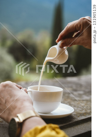 Pouring Milk into Coffee Cup Outdoors Pouring Milk into Coffee Cup Outdoors 131905139