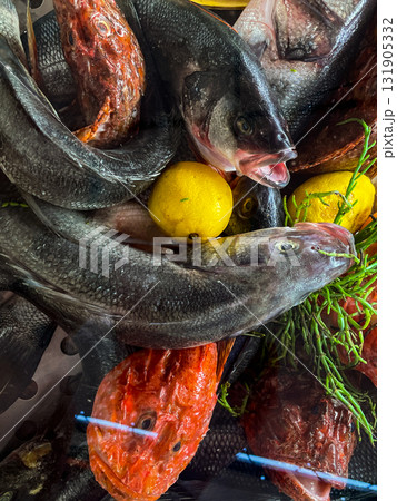 Raw fish fillet with tomatoes and herbs. Against a dark background. Seafood on ice at the fish market. Seafood. Healthy diet eating concept. View from above. Raw fish fillet with tomatoes and herbs. Against a dark background. Seafood on ice at the fish market. Seafood. Healthy diet eating concept. View from above. 131905332
