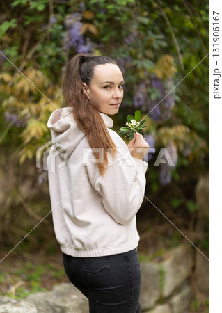 Woman looking back holding small white flowers Woman looking back holding small white flowers 131906167