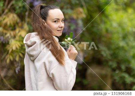 Woman holding white flowers, looking back, smiling 131906168