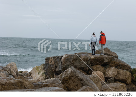 Couple contemplating future standing on a rocky coastline 131906220