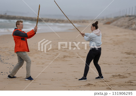 People playing with sticks on sandy beach People playing with sticks on sandy beach 131906295