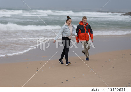 Young couple walking on sandy beach enjoying leisure time Young couple walking on sandy beach enjoying leisure time 131906314
