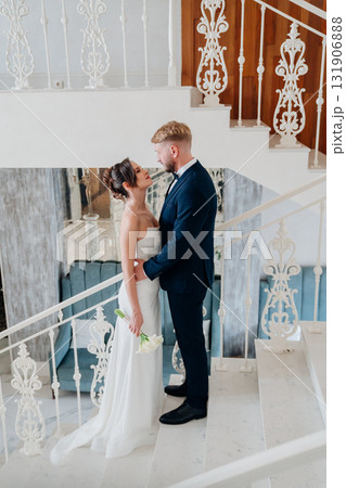 Beautiful and happy bride and groom on a large beautiful staircase. Beautiful and happy bride and groom on a large beautiful staircase. 131906888