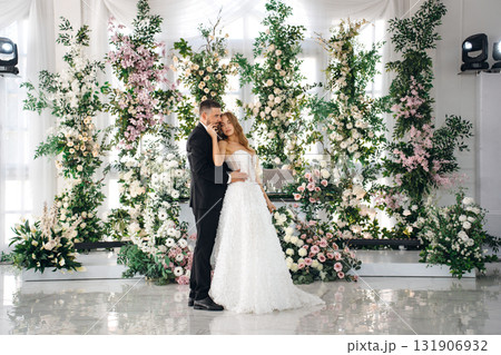 newlyweds embrace affectionately in a room decorated with many flowers newlyweds embrace affectionately in a room decorated with many flowers 131906932