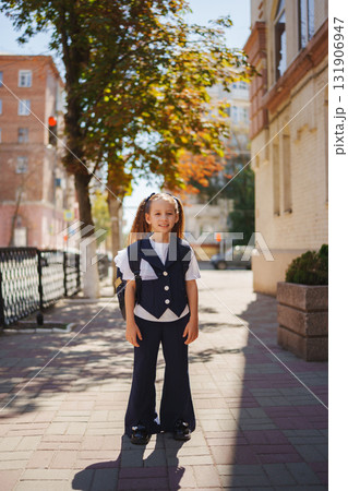 Young girl in school uniform standing on sunny street at morning 131906947