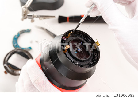 the hands of the master with gloves and a broken lens of a professional camera. the hands of the master with gloves and a broken lens of a professional camera. 131906985