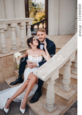 A bride and groom in love and happy on the steps at the entrance to a building. 131906989