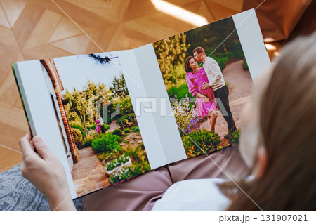 woman is holding and flipping through a photo book with a pregnancy photo shoot woman is holding and flipping through a photo book with a pregnancy photo shoot 131907021