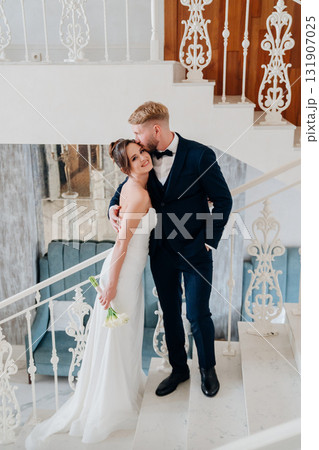 Beautiful and happy bride and groom on a large beautiful staircase. 131907025