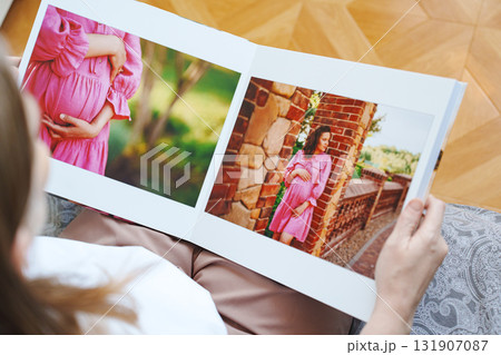 woman is holding and flipping through a photo book with a pregnancy photo shoot woman is holding and flipping through a photo book with a pregnancy photo shoot 131907087