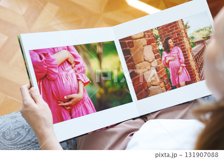 woman is holding and flipping through a photo book with a pregnancy photo shoot woman is holding and flipping through a photo book with a pregnancy photo shoot 131907088