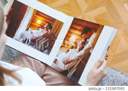 woman is holding and flipping through a photo book with a pregnancy photo shoot 131907091