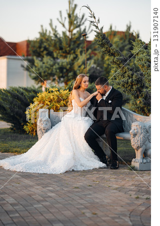 Gentle and happy bride and groom at sunset in the park on a bench. Gentle and happy bride and groom at sunset in the park on a bench. 131907140