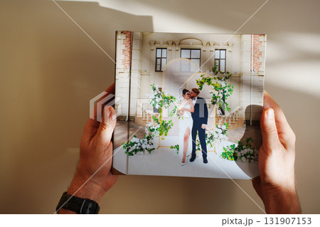 hands with a photo book with wedding photos on a white table hands with a photo book with wedding photos on a white table 131907153