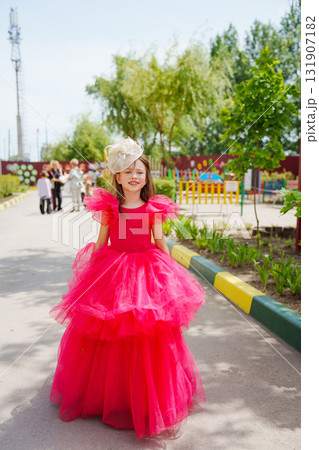 A girl in a lush pink dress and hat on a walk 131907182