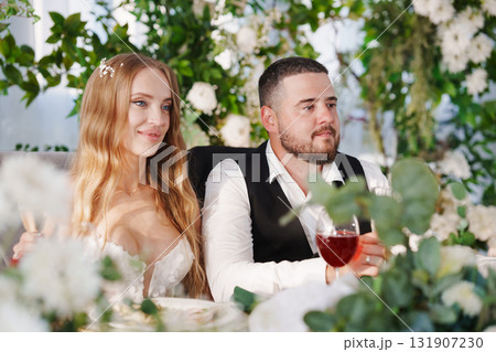 The bride and groom at the newlyweds' table, decorated with many flowers. The bride and groom at the newlyweds' table, decorated with many flowers. 131907230