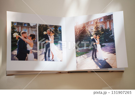 an open photo book with wedding photos on a white table 131907265