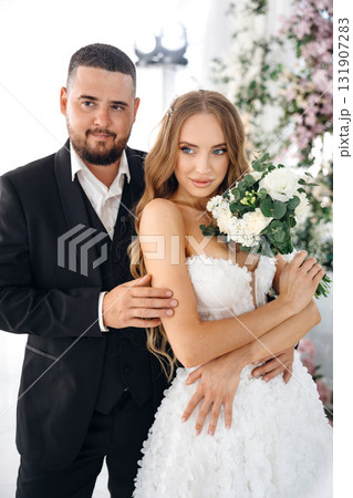 Beautiful and gentle bride and groom on the background of flowers in the decor. 131907283