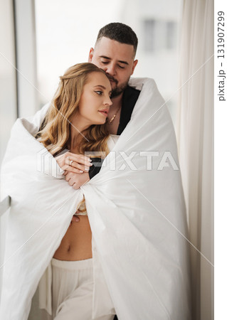 A gentle and romantic man and woman wrapped in a blanket on the windowsill 131907299