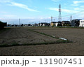 収穫の終わったの畑と家並みと送電線 131907451