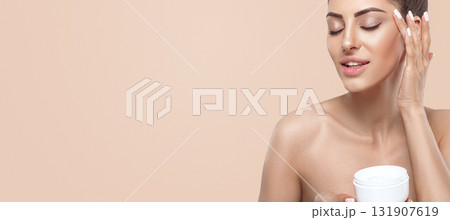 Beauty Woman Concept. Skin care. Portrait of female model holding and applying cosmetic moisturizing cream and touch own face. Nude make-up. Skin Protection.Panorama, baner With Copy Space. Beauty Woman Concept. Skin care. Portrait of female model holding and applying cosmetic moisturizing cream and touch own face. Nude make-up. Skin Protection.Panorama, baner With Copy Space. 131907619