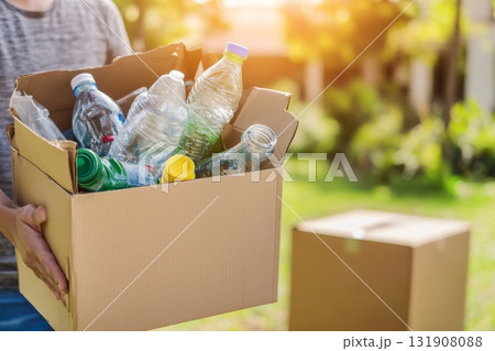 Cropped unrecognized person carrying crate of empty plastic bottles. Recycling plastic concept. Hands with Recycle Bin. Littering of environment. Problem of global plastics pollution of the Earth. 131908088