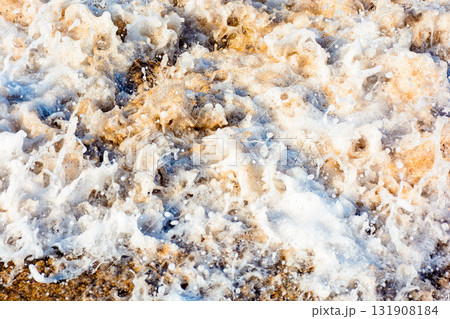 texture of sea foam on the sandy beach. scenic aqua splash. closeup natural abstract background on a sunny day. summer vacation season. frozen moment of salt water meets golden sand and make art mess 131908184