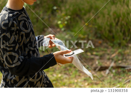 Orienteering athlete running through a summer forest with a map and compass. 131908358